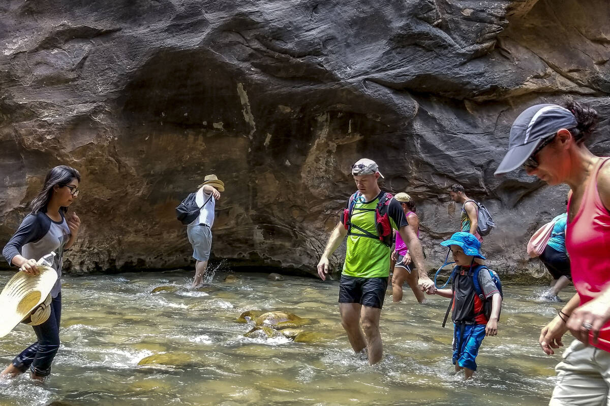 In this July 14, 2017, file photo, Zion National Park visitors walk along The Narrows, a river ...