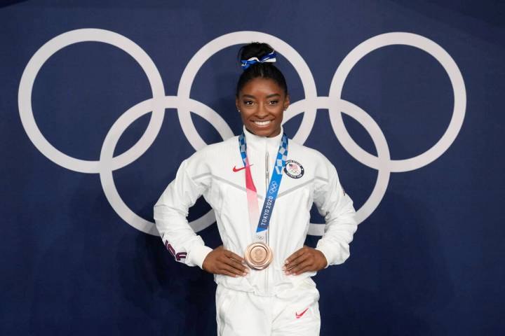 FILE - Simone Biles, of the United States, poses wearing her bronze medal from balance beam com ...