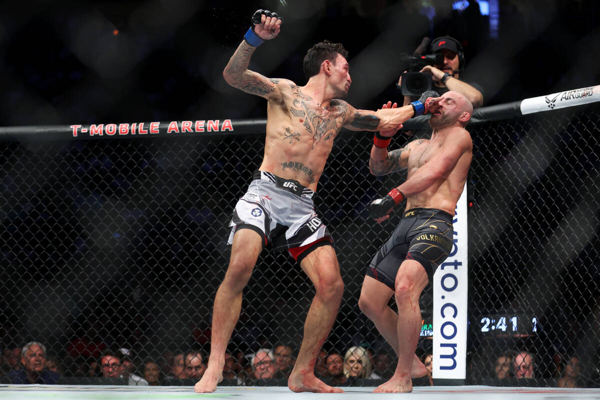 Max Holloway, left, lands a punch against Alexander Volkanovski in the third round of a feather ...