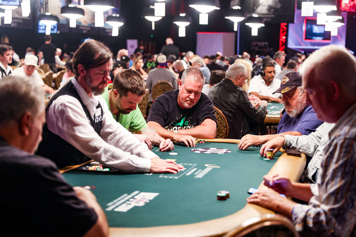Craig Reifsnyder, of Pennsylvania, center, plays poker during the first flight of the $10,000 M ...