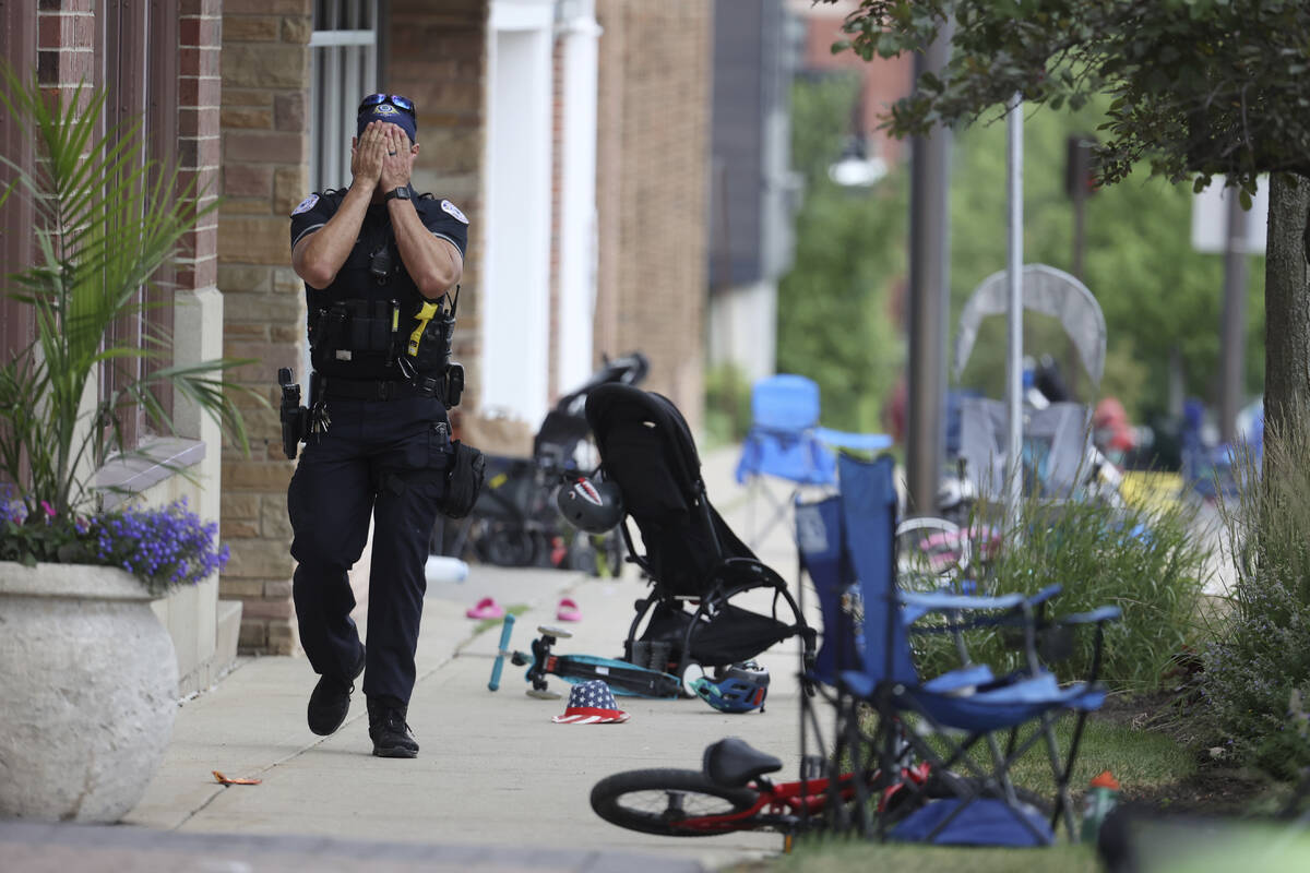 A Lake County police officer walks down Central Ave in Highland Park on Monday, July 4, 2022, a ...