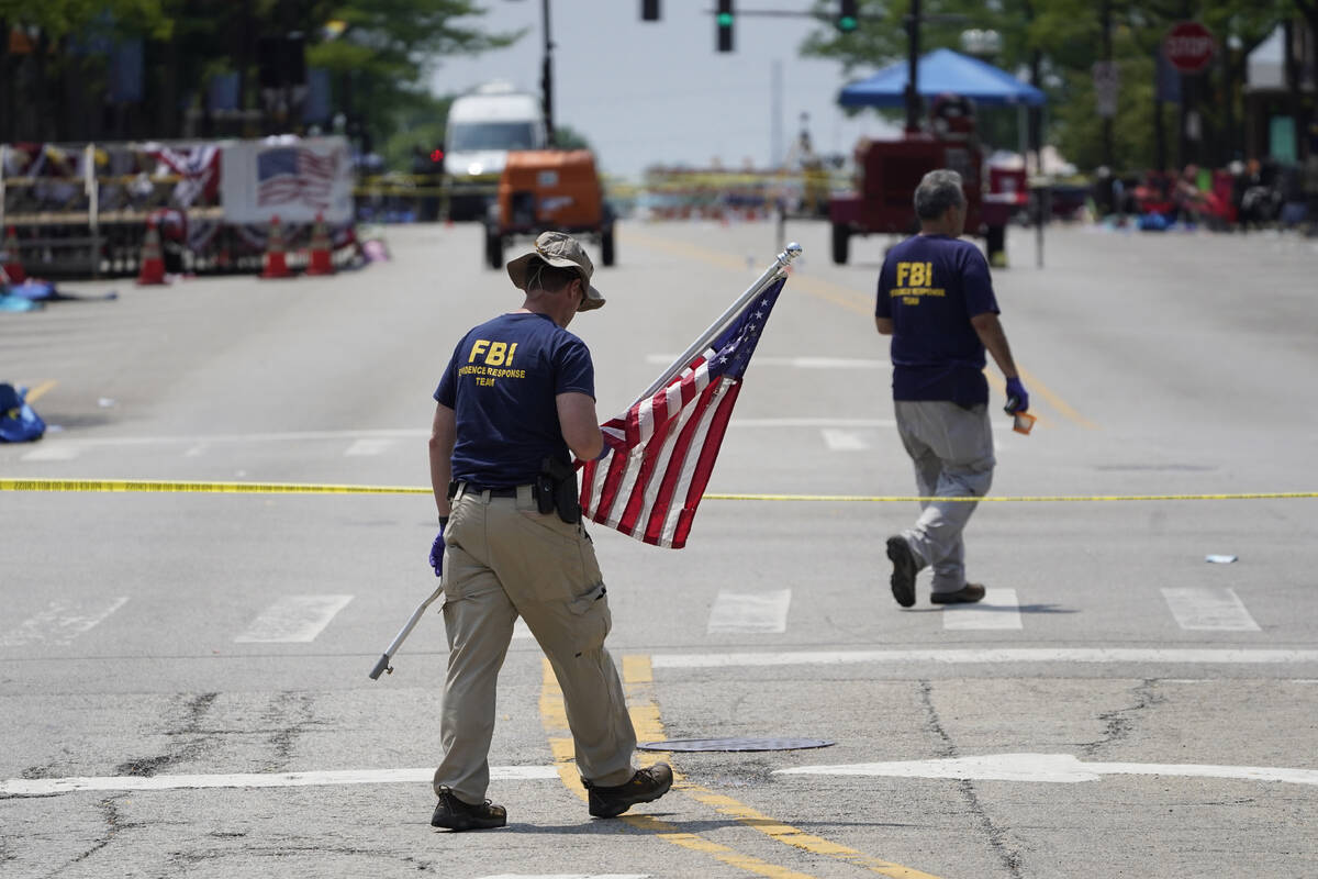 A member of the FBI's evidence response team removes an American flag one day after a mass shoo ...