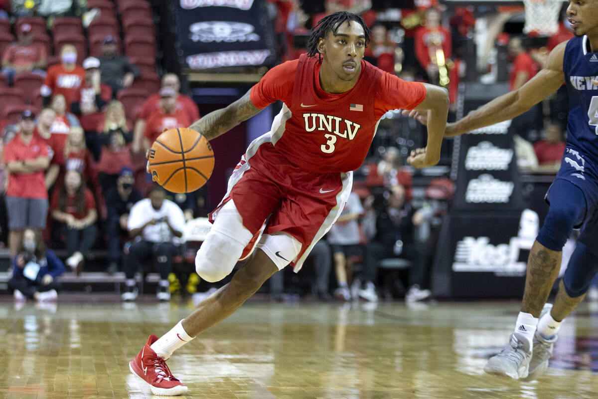 UNLV Rebels forward Donovan Williams (3) dribbles up the court while Nevada Wolf Pack guard Des ...