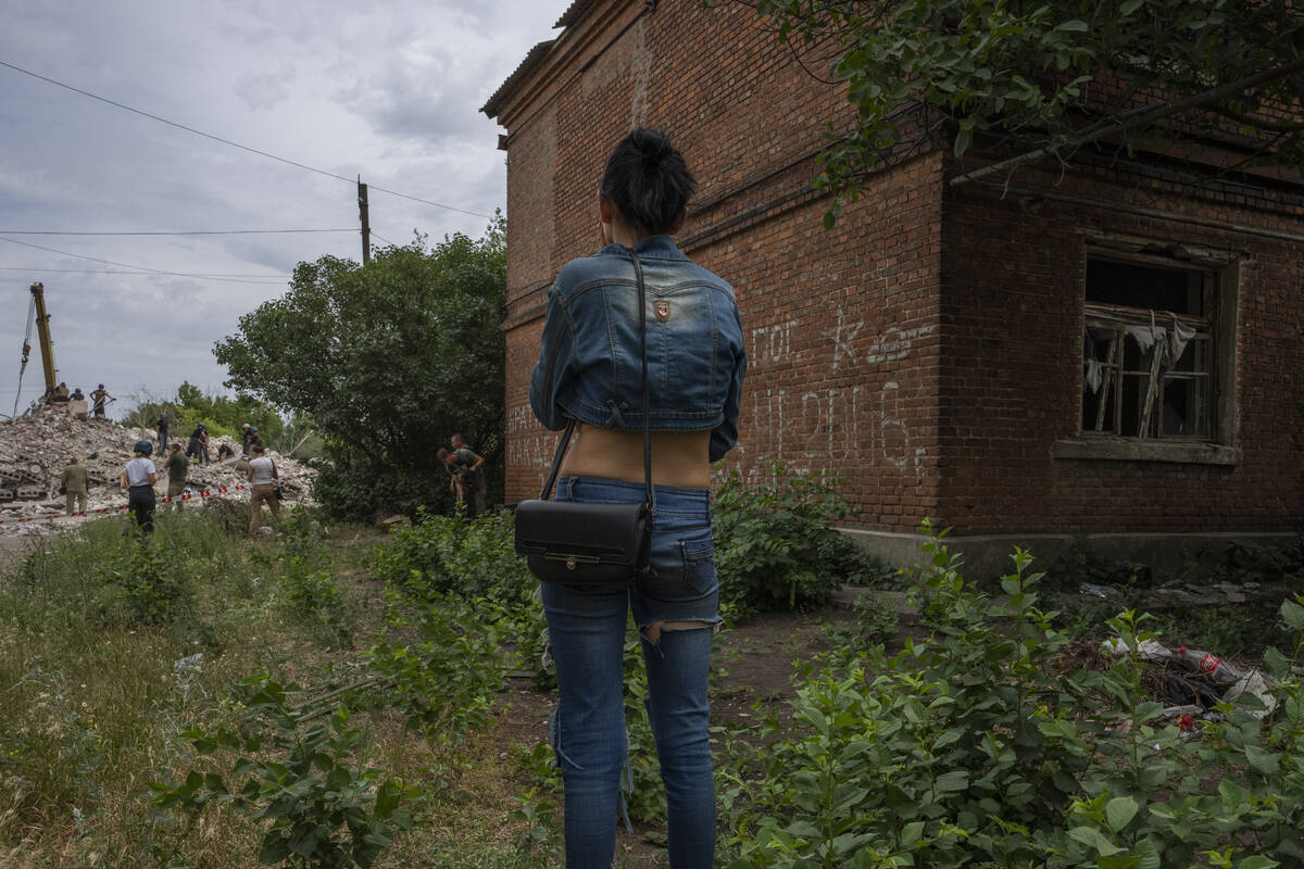 A woman looks at rescue workers at scene in the aftermath of a Russian rocket that hit an apart ...