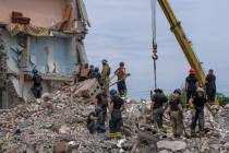 Rescue workers sift through rubble at the scene in the after math of a Russian rocket that hit ...