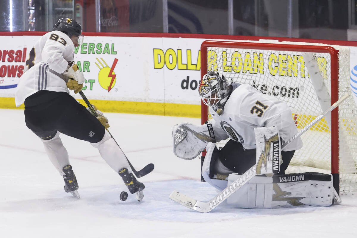 Golden Knights goaltender Isaiah Saville defends the net as forward Daniel D’Amato looks ...