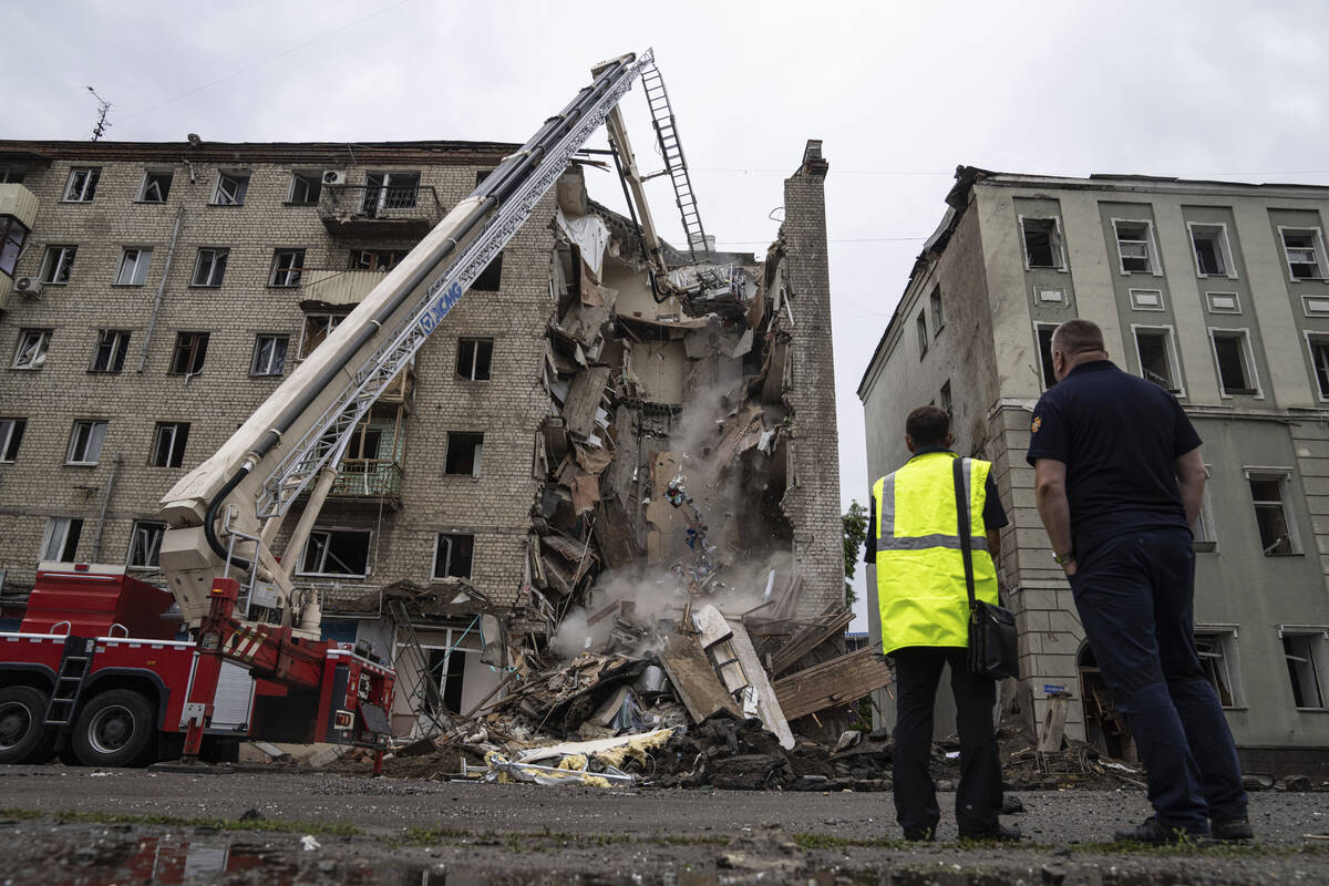 Rescue workers clear the rubble of a destroyed building after a Russian attack in a residential ...