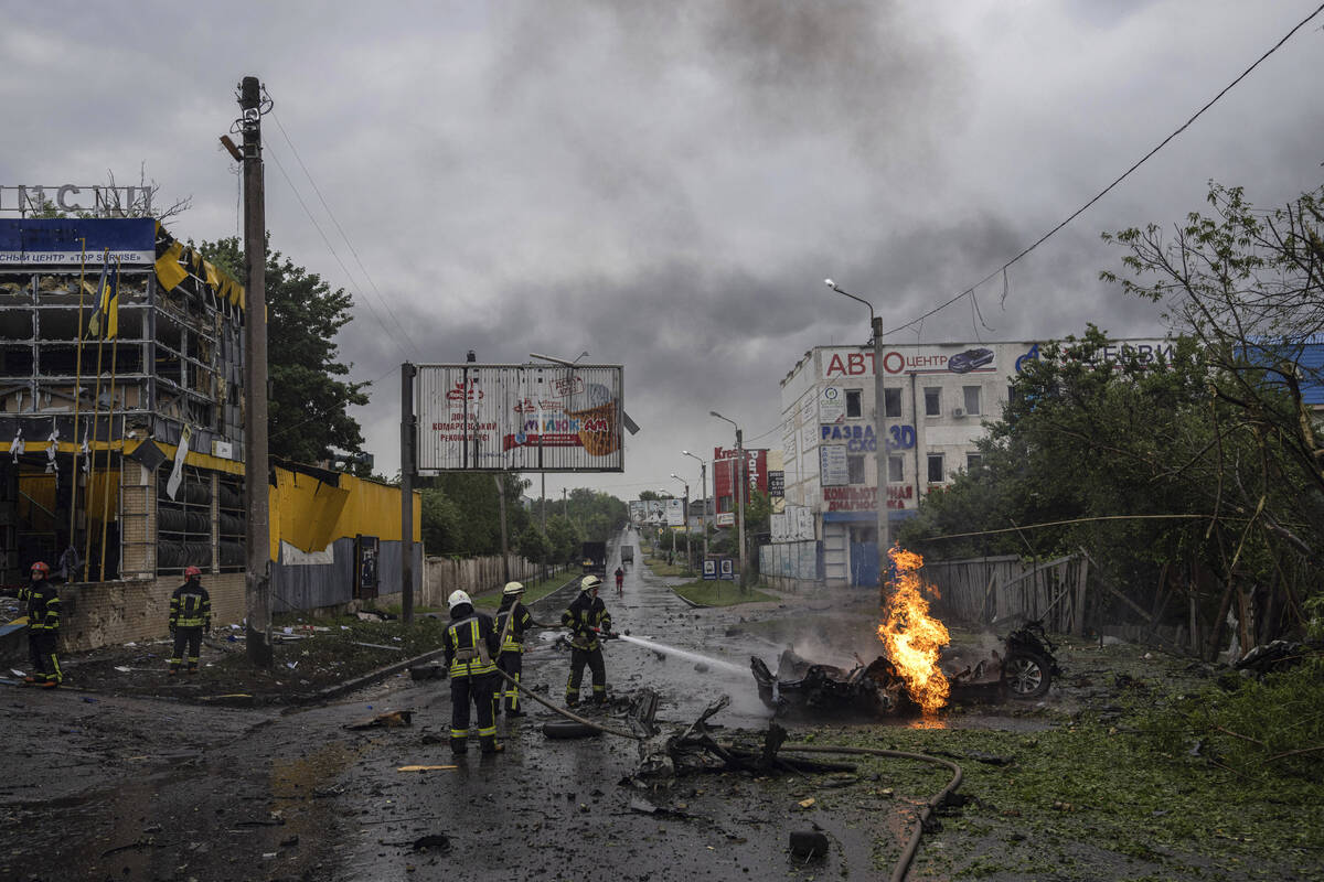 Rescue workers put out the fire of a destroyed car after a Russian attack in a residential neig ...