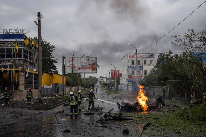 Rescue workers put out the fire of a destroyed car after a Russian attack in a residential neig ...