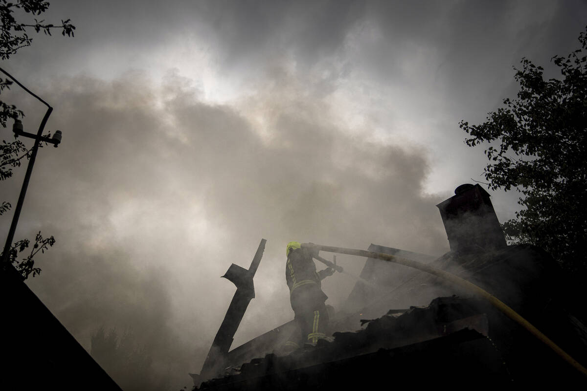 A rescue worker puts out the fire on a destroyed house after a Russian attack in a residential ...