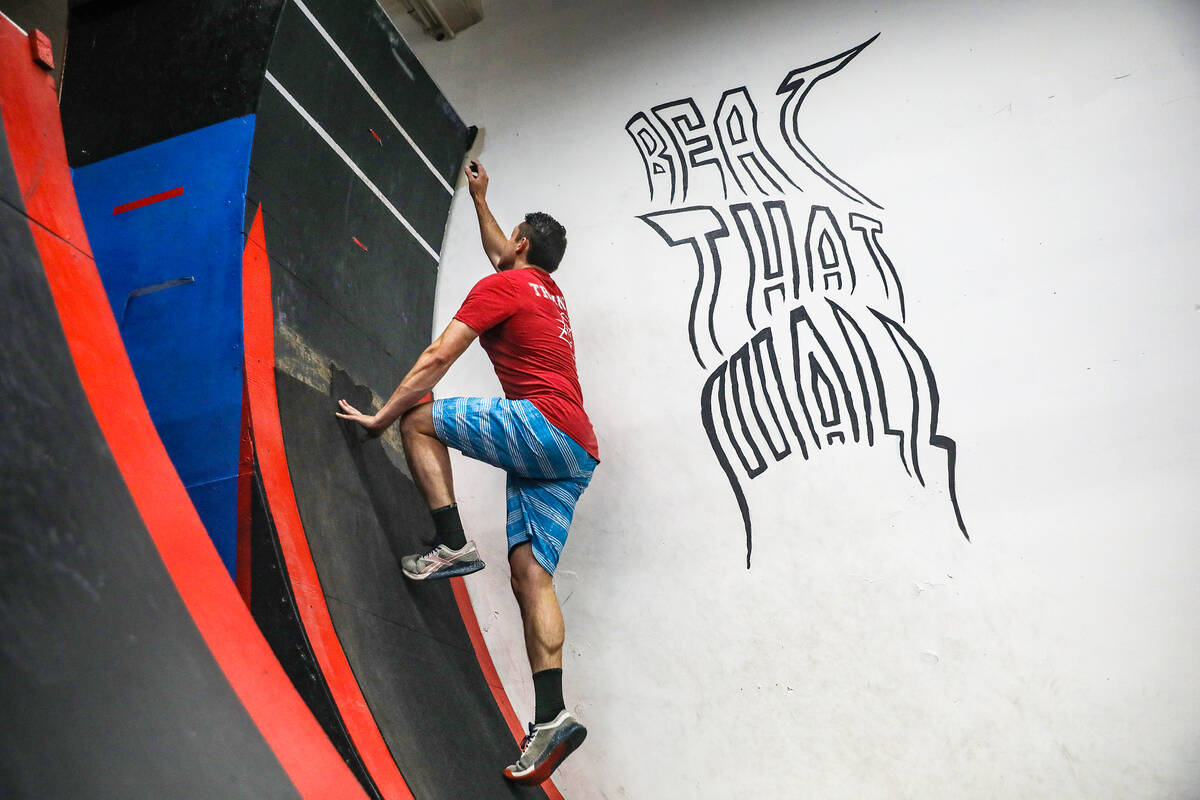 Manager Parker Gatewood shows how to ascend the warped wall obstacle at Rhino Ninja Gym in Las ...