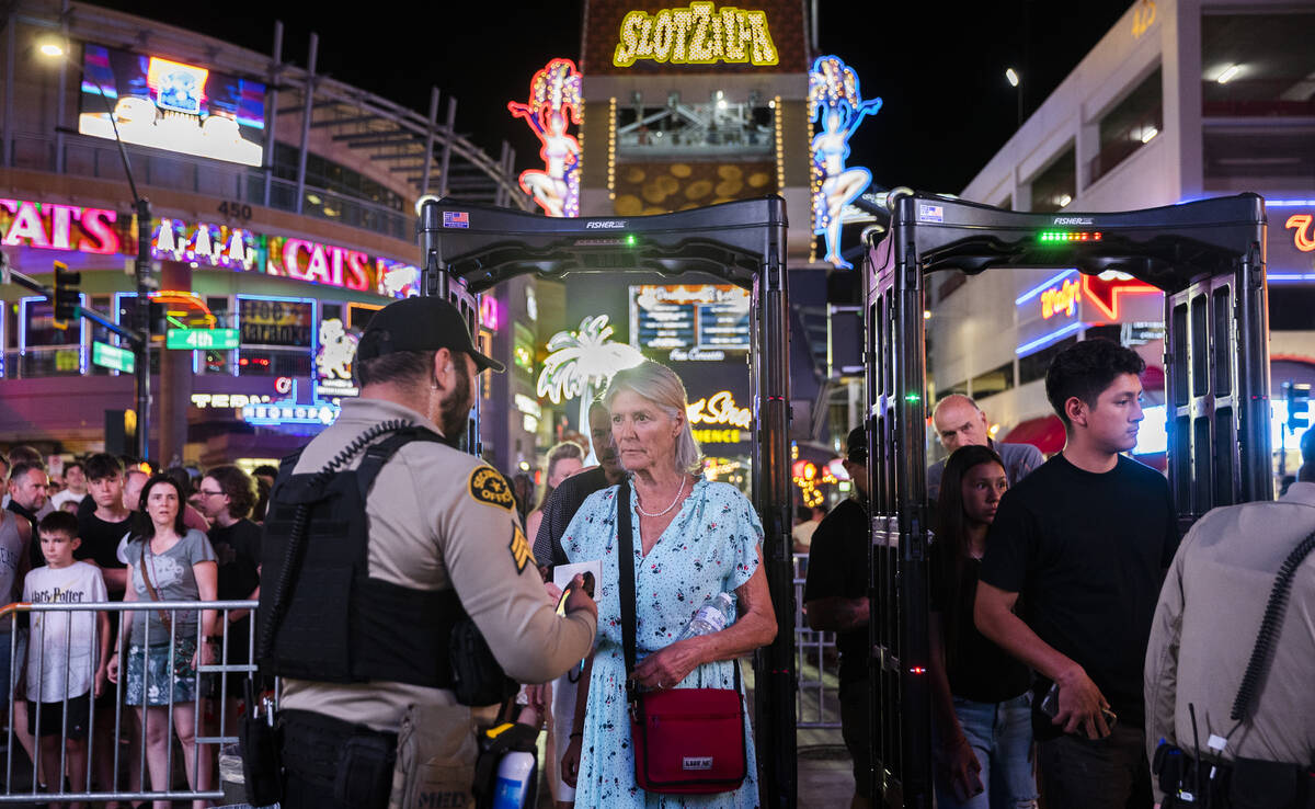 Security officers screen people as they walk through a metal detector before entering the Fremo ...