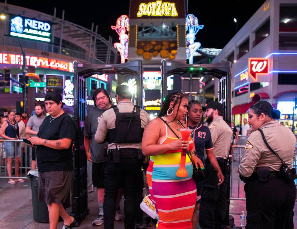 Security officers screen people as they walk through a metal detector before entering the Fremo ...