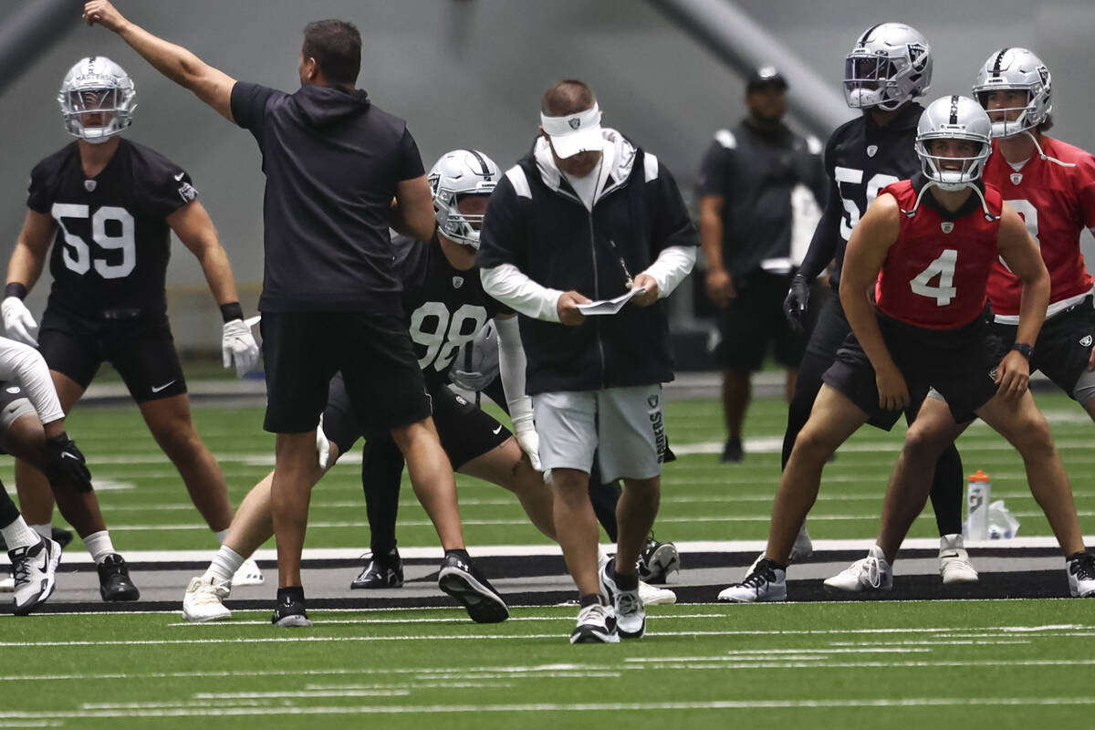 Raiders head coach Josh McDaniels, center, walks as players stretch during minicamp training at ...