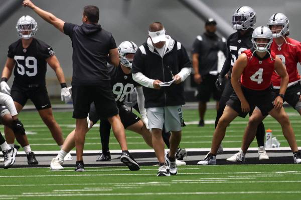 Raiders head coach Josh McDaniels, center, walks as players stretch during minicamp training at ...