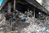 Rescuers work at the scene of a building that was damaged by a deadly Russian missile attack in ...