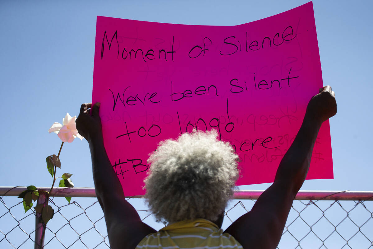 Cariol Horne, 54, holds up a sign as she stands outside the fenced-off parking lot outside Tops ...