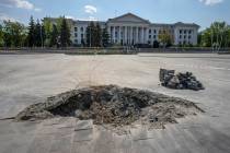 A crater in the aftermath of a Russian missile strike, in front of the city council hall buildi ...