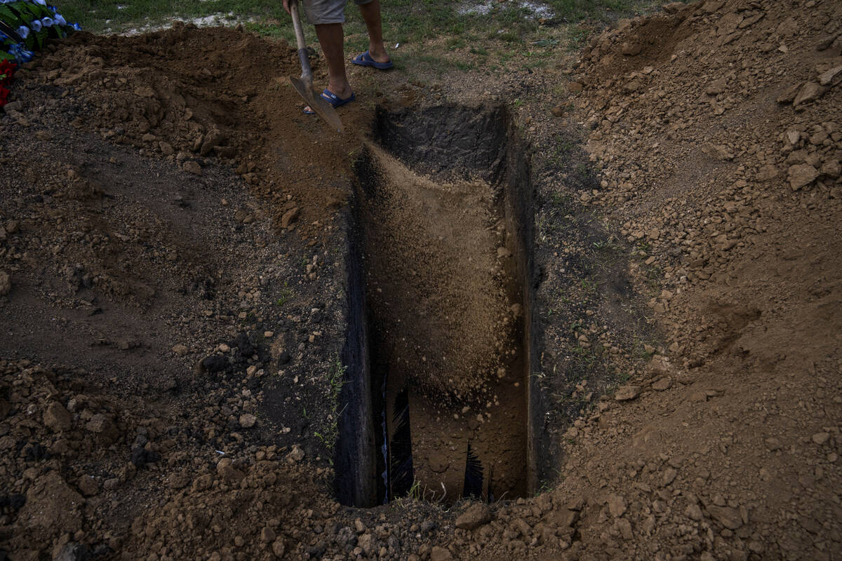 FILE A grave digger uses his shovel to throw dirt on the coffin of 40-year-old Volodymyr Mirosh ...