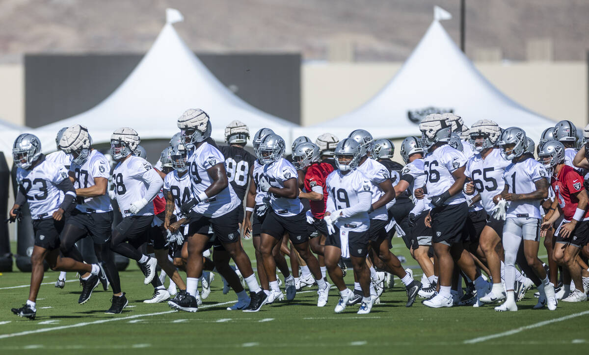 Players including center Andre James (68, left) run across the field during Raiders first pract ...