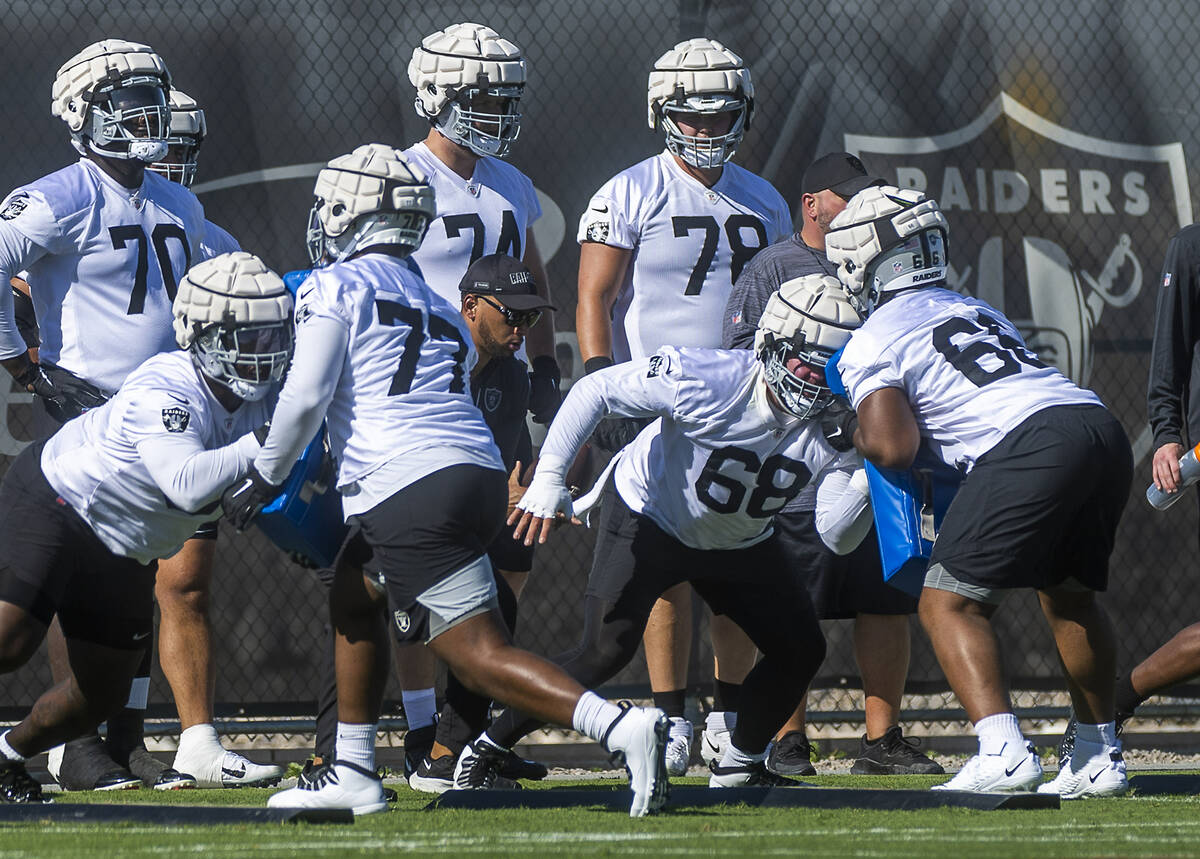 Center Andre James (68, middle) throws a block on guard Dylan Parham (66) in a drill with teamm ...