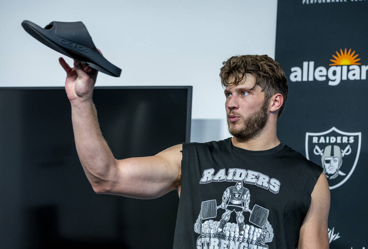 Tight end Foster Moreau (87) shows off his new OOFOS recovery sandals while speaking in a press ...