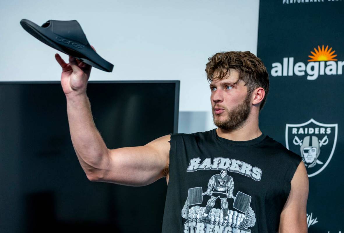 Tight end Foster Moreau (87) shows off his new OOFOS recovery sandals while speaking in a press ...