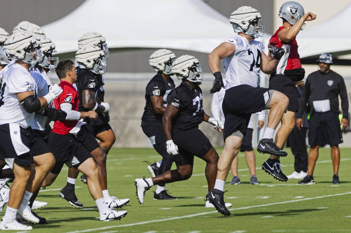 Raiders players, including quarterback Derek Carr (4) and tight end Kolton Miller (74) warm up ...