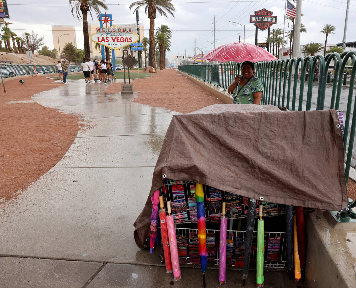 Rina Williamson of Las Vegas sells umbrellas and other souvenirs during a brief rainfall at the ...