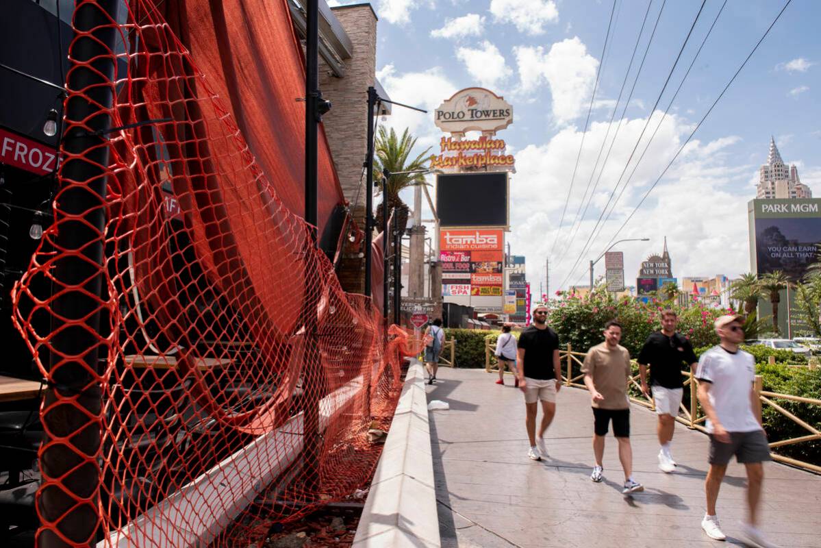 Pedestrians walk through the closed Hawaiian Marketplace on Las Vegas Boulevard on Monday, July ...