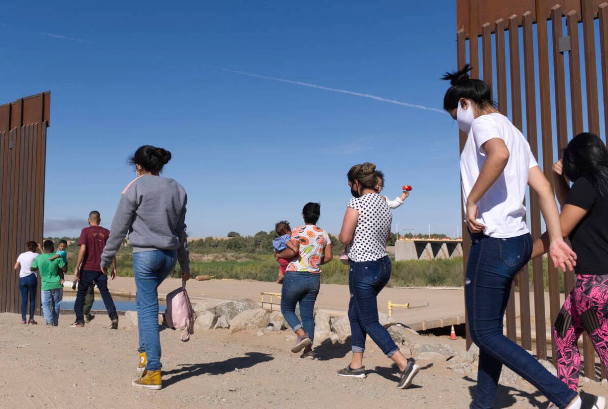 FILE - A group of Brazilian migrants make their way around a gap in the U.S.-Mexico border in Y ...