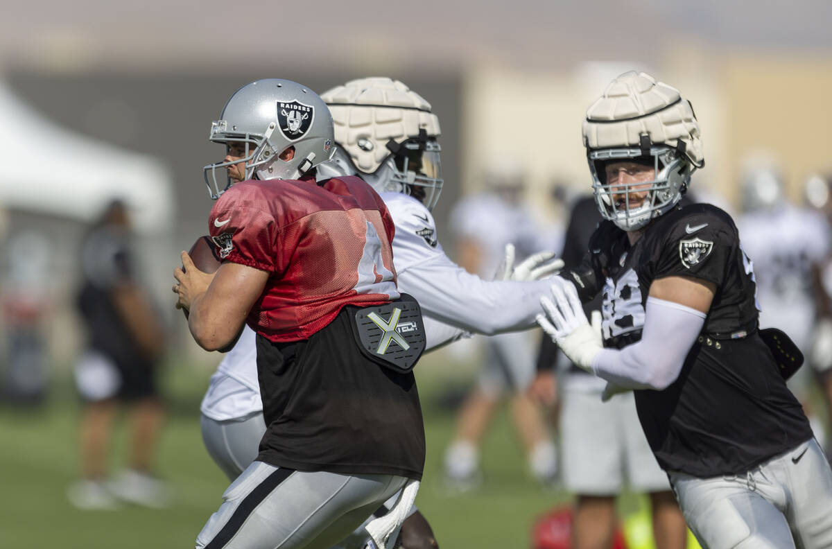 Raiders defensive end Maxx Crosby (98) pursues quarterback Derek Carr (4) with offensive linema ...