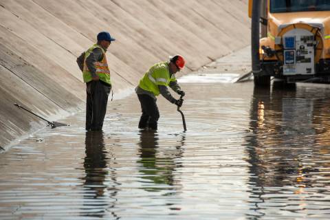 Nevada DOT workers work to clear flood waters from West Washington Ave. near North Main St. on ...