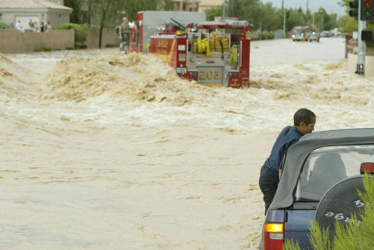 Juliette Lopez stands by her car at the flooded intersection of Rainbow Boulevard and Gowan Roa ...