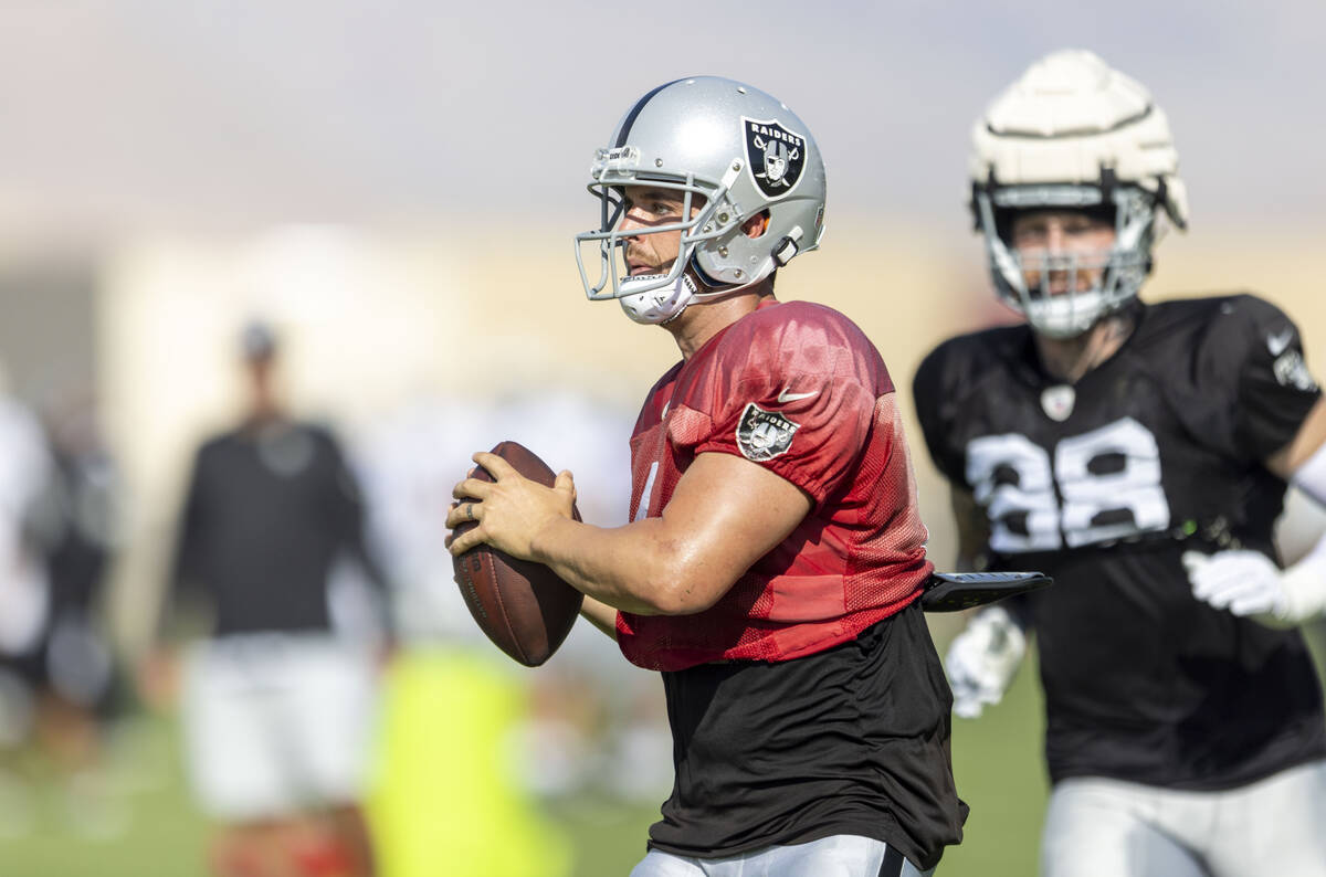 Raiders quarterback Derek Carr (4) rushes with defensive end Maxx Crosby (98) looking on during ...