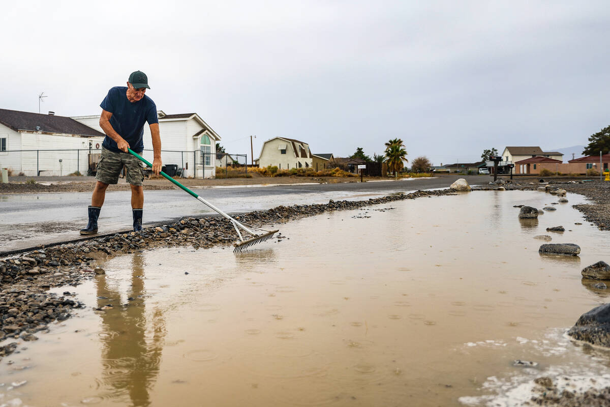 Lonny Young diverts water on his street after a flash flood hit the region in Pahrump, Nev., Su ...