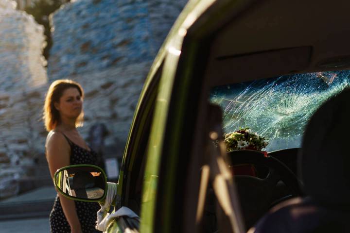 A woman looks at a civilian's car shot at by Russian forces exhibited at Mykhailivs'ka Square a ...