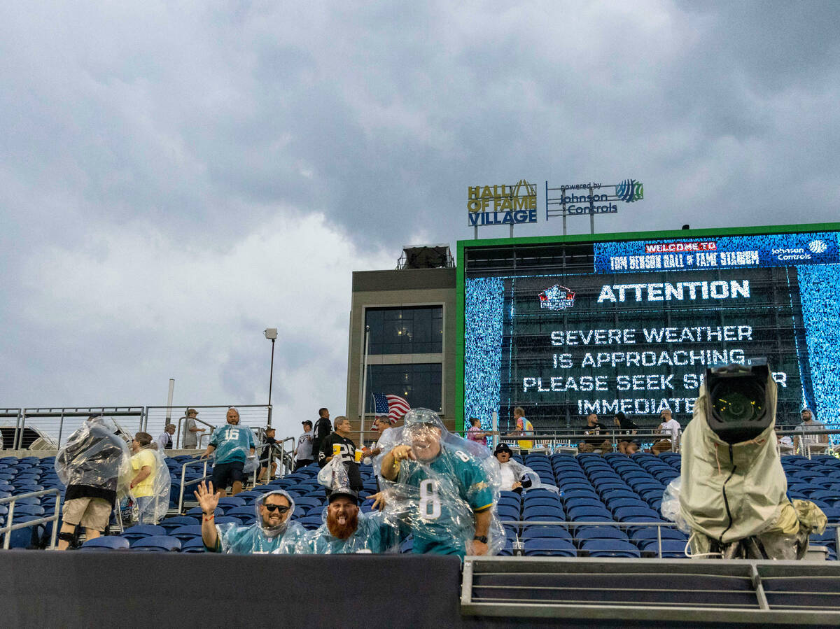Fans stay in their seats during a severe weather alert that delayed the start of the NFL Hall o ...