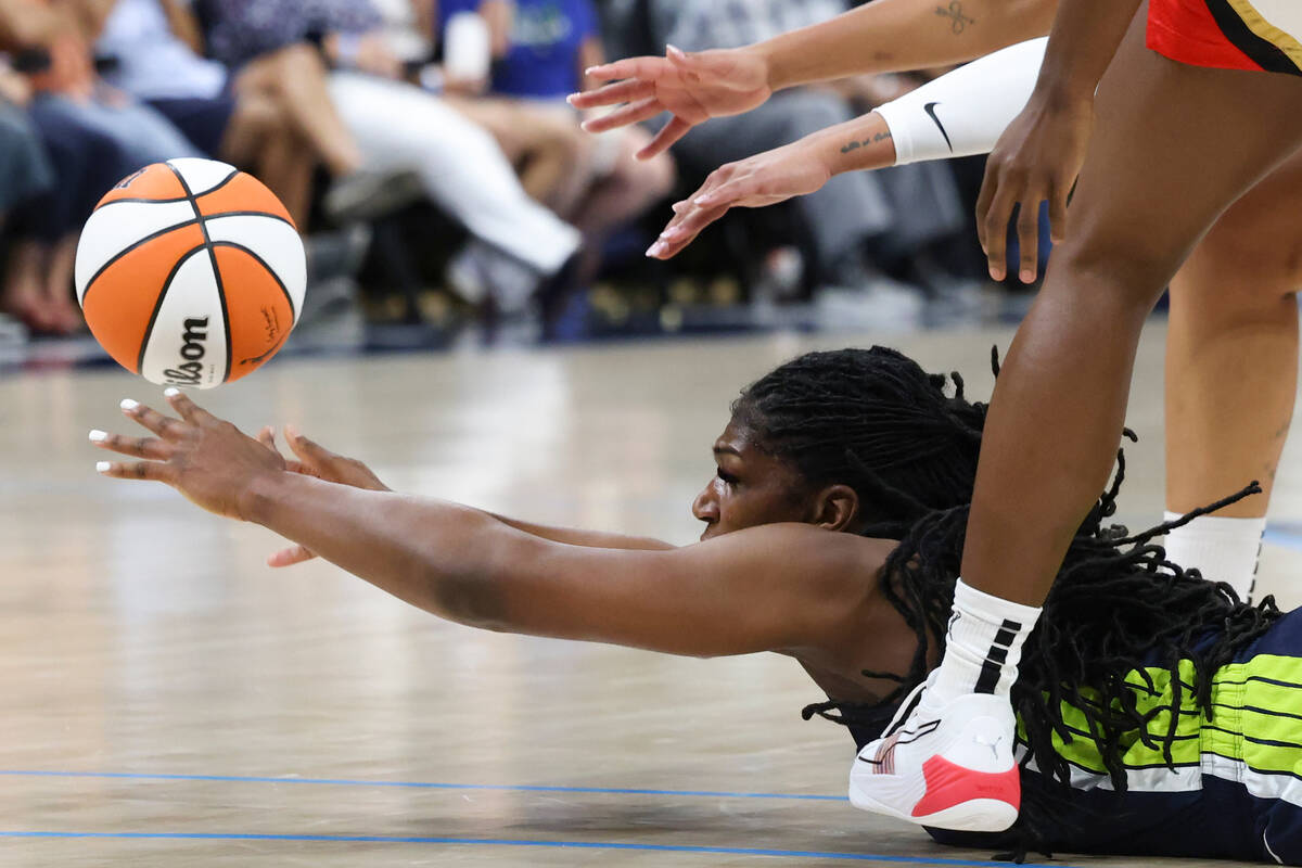 Dallas Wings center Teaira McCowan (7) passes the ball to a teammate while sprawled across the ...