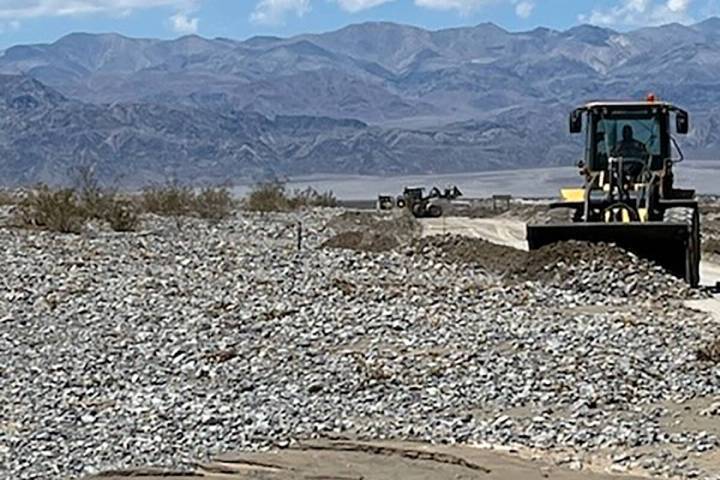 Heavy equipment removes several feet of rocks and flood debris from a road in Death Valley on S ...