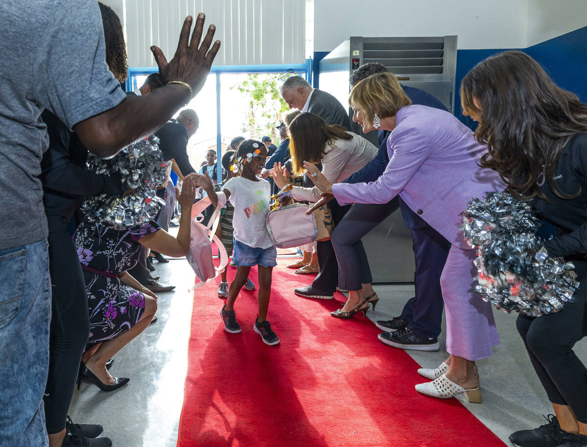U.S. Rep. Susie Lee, right, gives a high five to a student while joined by many others in a red ...