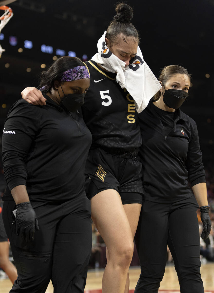 Las Vegas Aces forward Dearica Hamby (5) is escorted off the court by athletic trainers with an ...