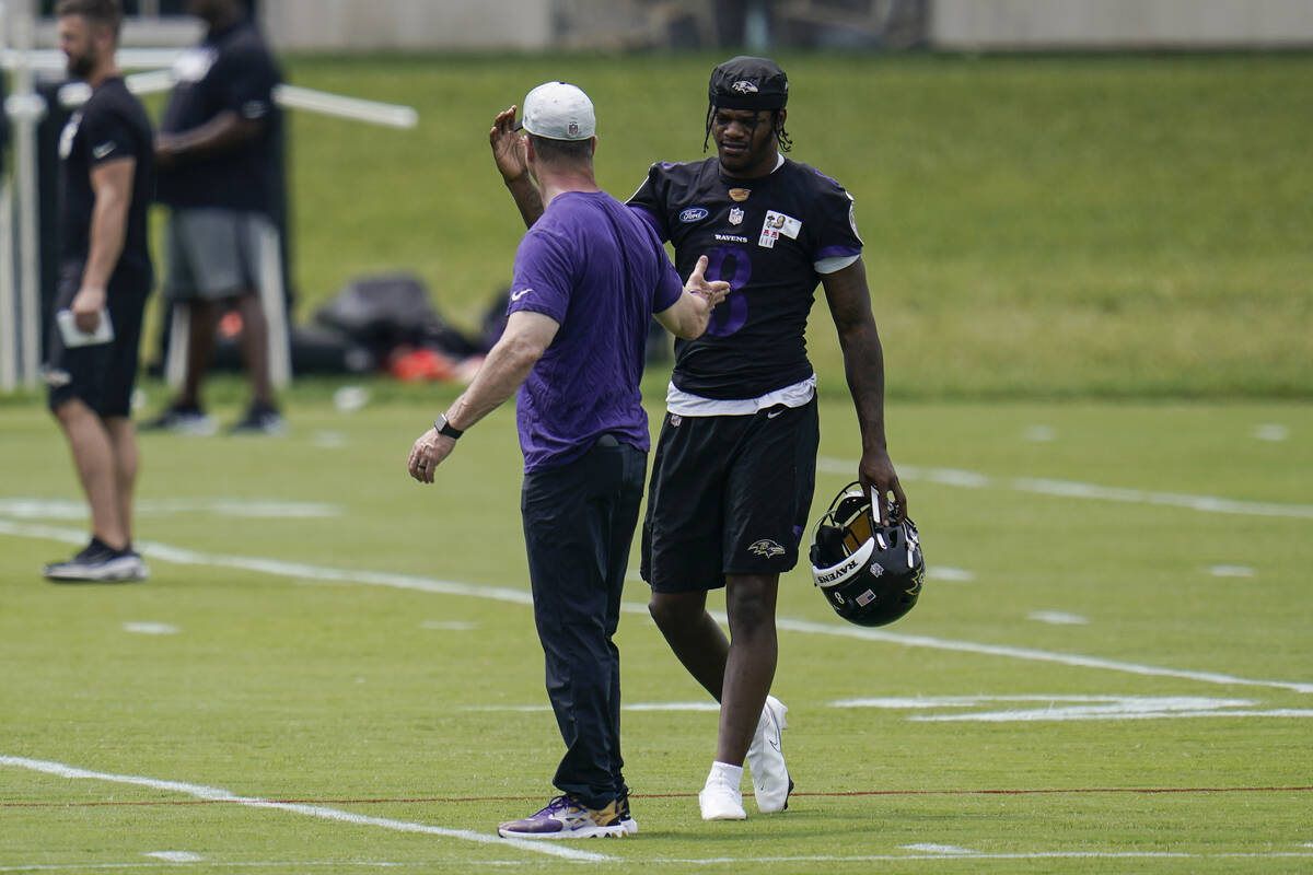 Baltimore Ravens quarterback Lamar Jackson, right, talks with head coach John Harbaugh during t ...