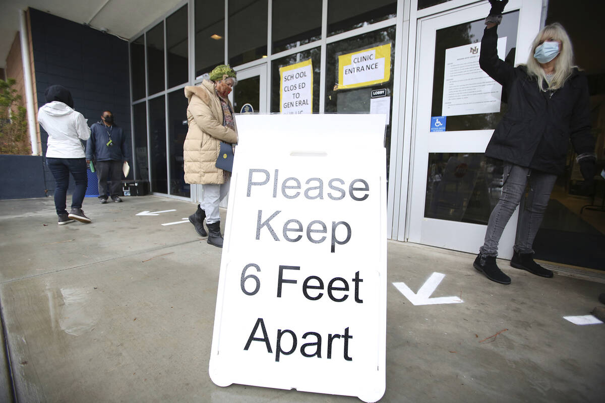 A sign asks those getting vaccinated to keep 6 feet apart during the vaccination event, Wednesd ...