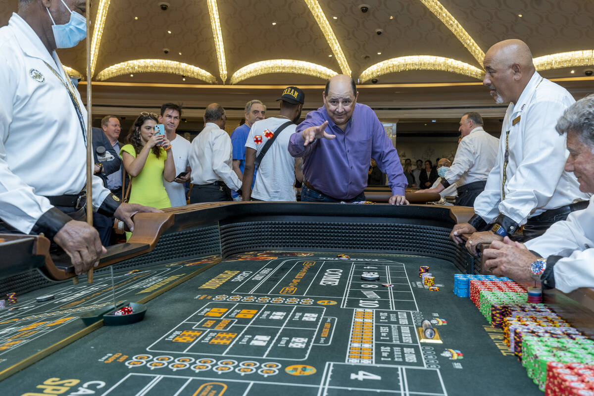 Gambler Juan Fresquez Jr., of Texas, center, tosses the first dice in craps at Caesars as they ...