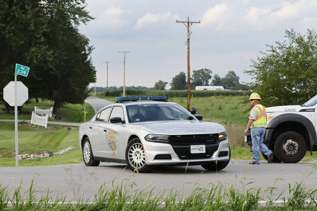 A Clinton County employee helps direct traffic as an Ohio State Highway Patrol vehicle leaves t ...