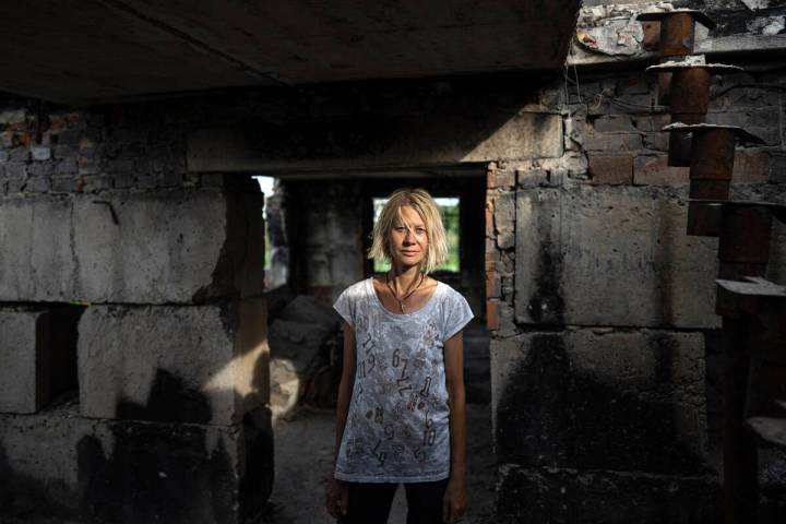 Zhanna Dynaeva stands inside her house which was destroyed by Russian bombardment, in the vill ...