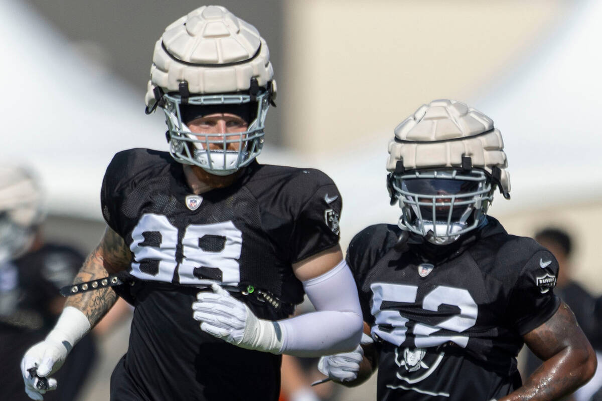 Raiders defensive end Maxx Crosby (98) and linebacker Denzel Perryman (52) run to a drill durin ...