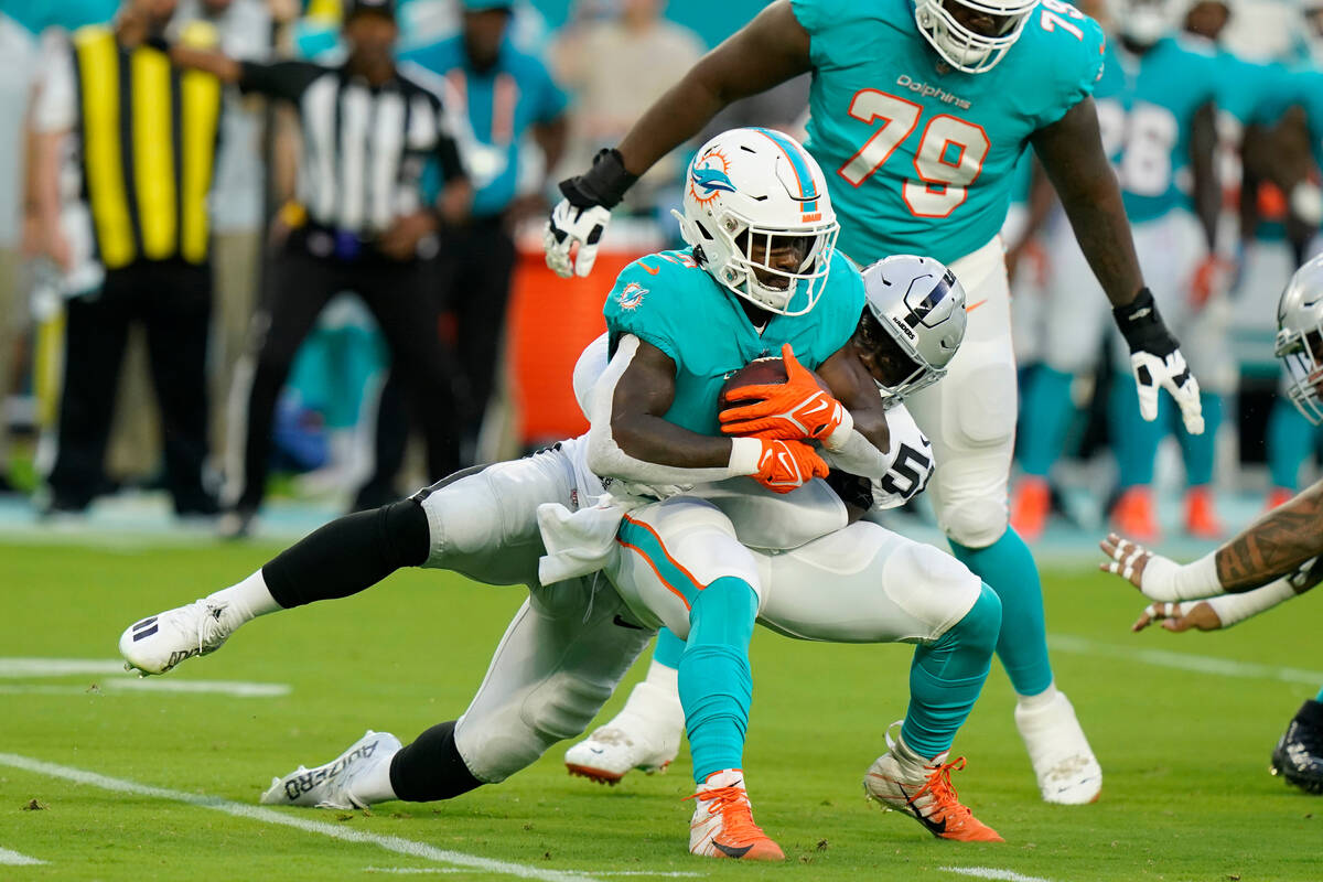 Las Vegas Raiders linebacker Darien Butler (58) tackles Miami Dolphins running back Chase Edmon ...