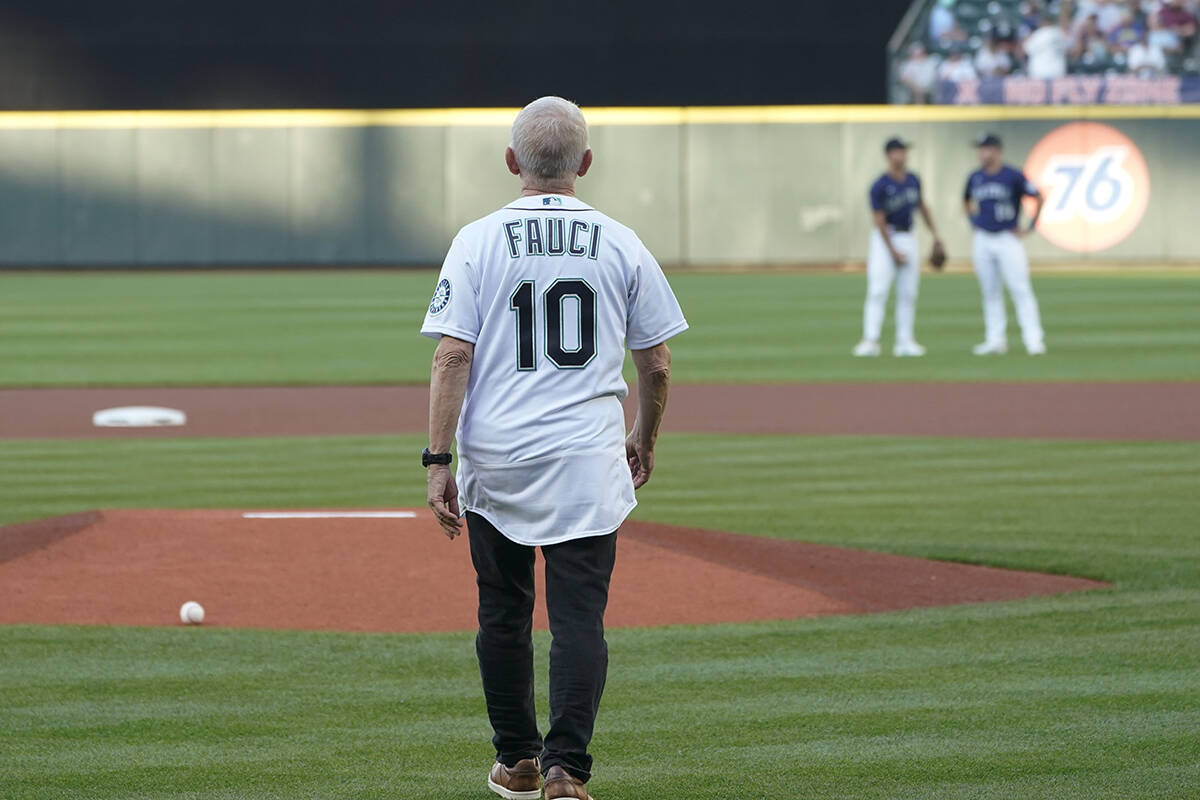 Dr. Anthony Fauci walks to the mound to throw out the first pitch before a baseball game betwee ...